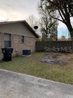 A brick house exterior features a side yard, a trash bin, and a wooden fence — 1100 WILSON ROAD, STARKE, FL