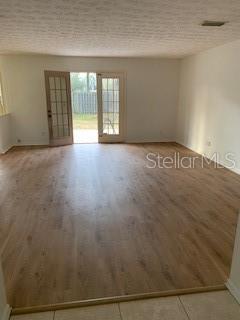An empty room with light wood-look flooring and glass-paned double doors leading outside — 1100 WILSON ROAD, STARKE, FL