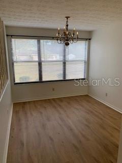 An empty room with light wood-look flooring, a large window, and a hanging chandelier — 1100 WILSON ROAD, STARKE, FL