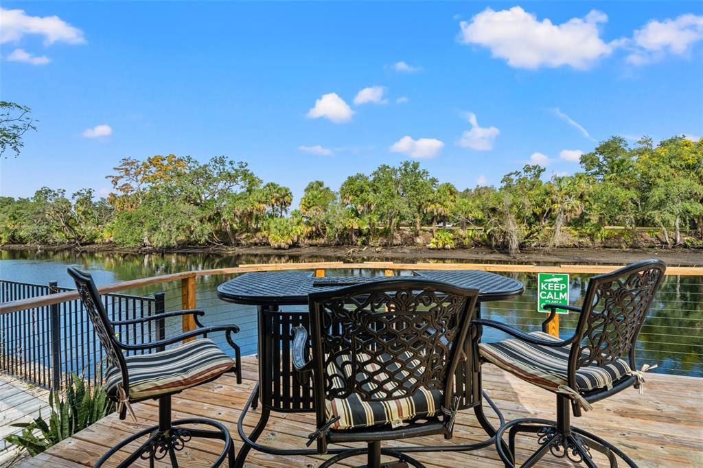 A wooden deck features a patio table and chairs overlooking a river and trees — 308 E HOLLYWOOD STREET, TAMPA, FL