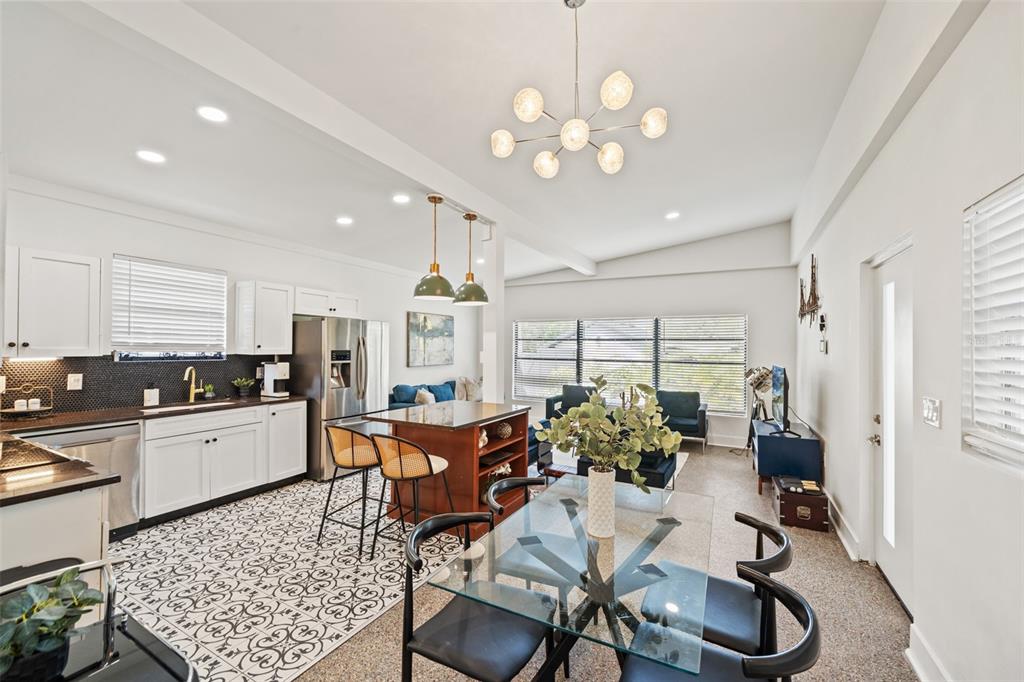 An open-concept kitchen and dining area features white cabinets, patterned tile flooring, and a chandelier — 308 E HOLLYWOOD STREET, TAMPA, FL