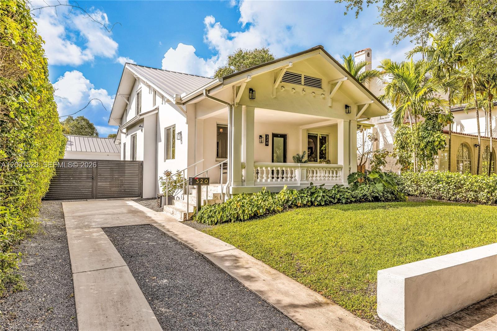 A white house with a front porch and a gravel driveway sits behind a lawn — 320 NE 88th St, El Portal FL 33138, EL PORTAL, FL