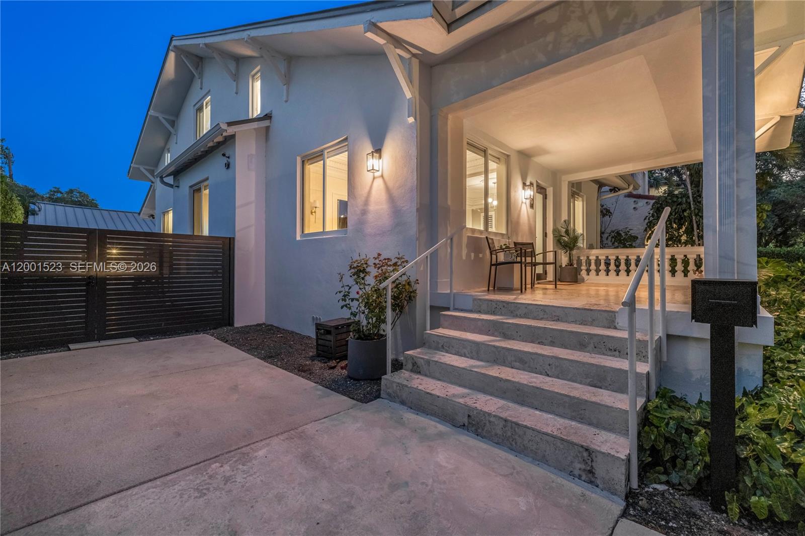 A white house exterior features a covered porch, stone steps, and a dark metal gate — 320 NE 88th St, El Portal FL 33138, EL PORTAL, FL
