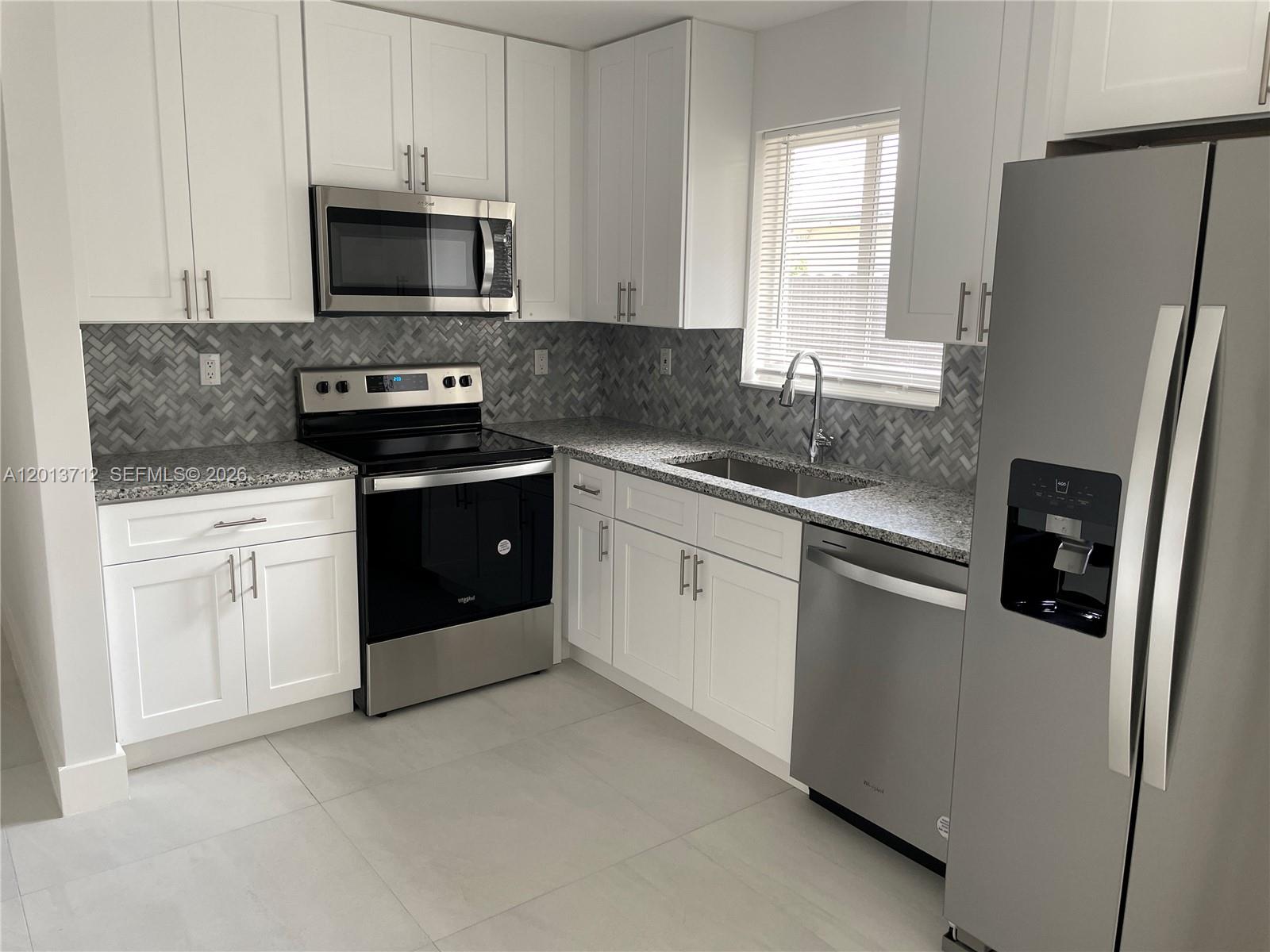A modern kitchen features white cabinets, stainless steel appliances, granite countertops, and a herringbone backsplash — 6820 SW 13th Ter # 6820, Miami FL 33144, MIAMI, FL