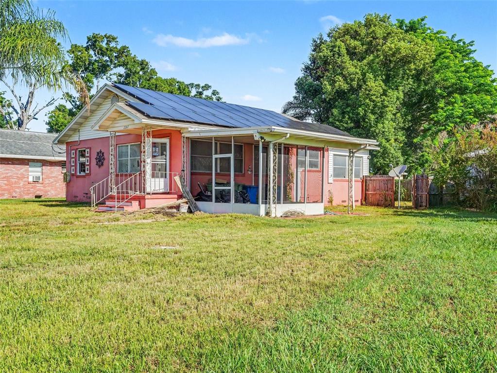 A pink house with a screened-in porch and solar panels on the roof — 2207 AVENUE B NW, WINTER HAVEN, FL