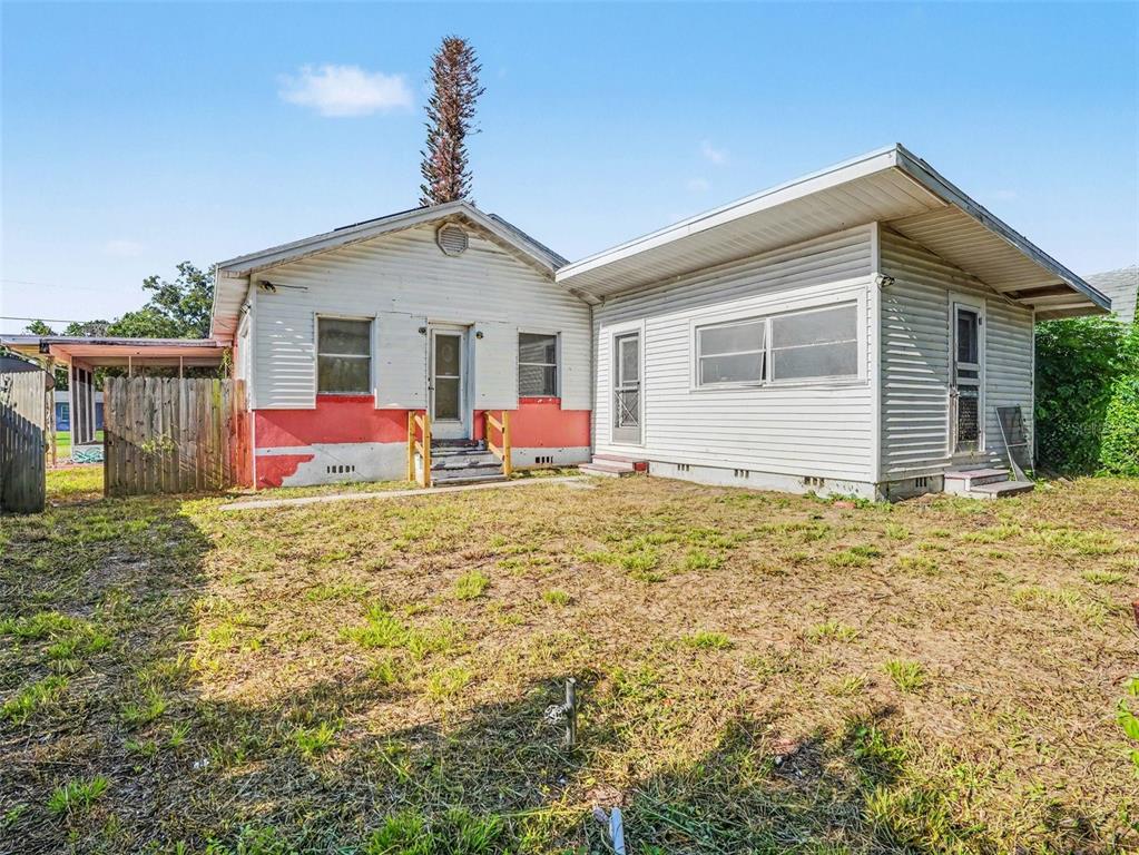 The exterior of a house with white siding, a red foundation, and a grassy backyard — 2207 AVENUE B NW, WINTER HAVEN, FL