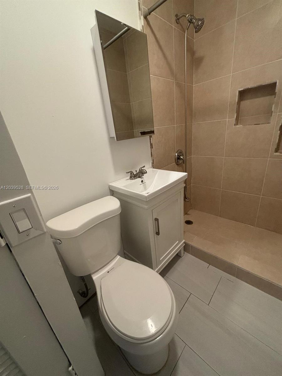 A small bathroom features a white toilet, a pedestal vanity, and a tiled walk-in shower — 2150 SW 76th Ct, Miami FL 33155, MIAMI, FL
