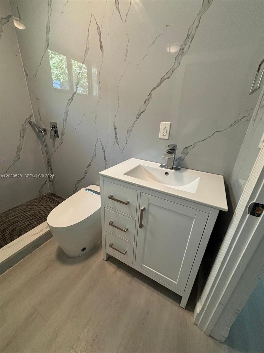 A modern bathroom features a white vanity, a toilet, and marble-patterned wall tiles — 2150 SW 76th Ct, Miami FL 33155, MIAMI, FL