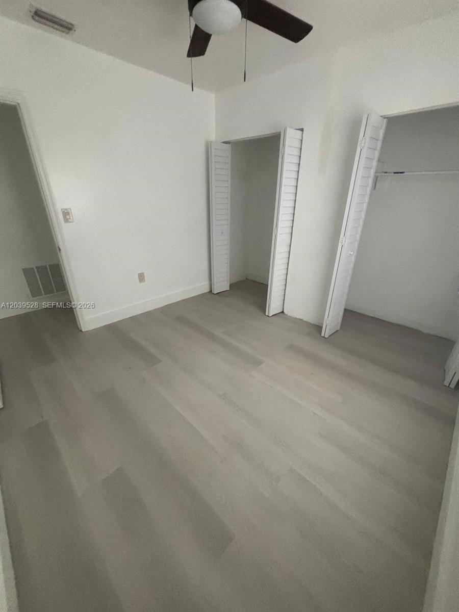 A bedroom features light-colored wood-look flooring, white walls, a ceiling fan, and two closets — 2150 SW 76th Ct, Miami FL 33155, MIAMI, FL
