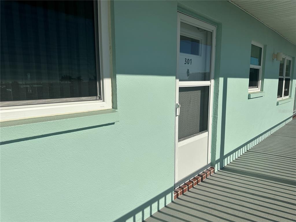 A light green exterior wall features a door labeled 301 and a window on a walkway — 1819 SHORE DRIVE S UNIT 307, SOUTH PASADENA, FL