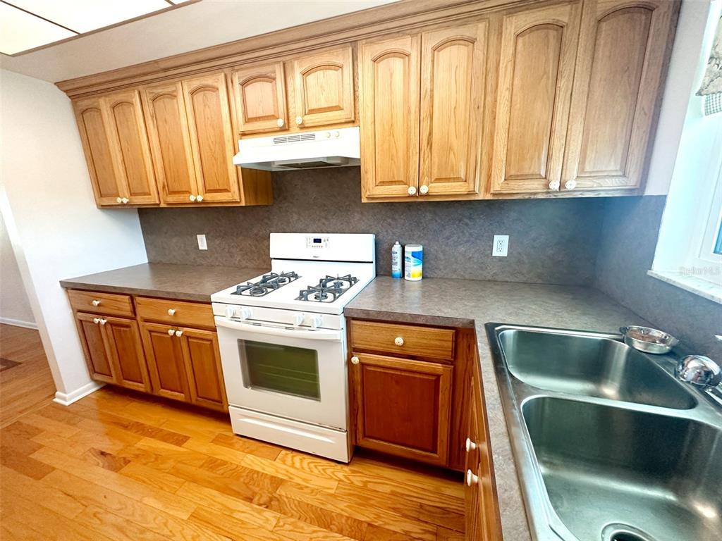 A kitchen features oak cabinets, a white gas stove, and dark countertops — 1819 SHORE DRIVE S UNIT 307, SOUTH PASADENA, FL