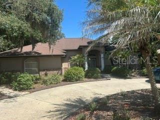 A single-story house with a brown roof, beige exterior, and a paved driveway — 2702 CLUBHOUSE DRIVE, PLANT CITY, FL