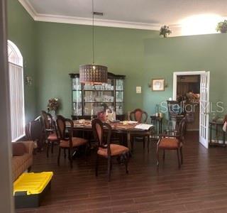 A dining room with green walls, a dark wood table, and a matching china cabinet — 2702 CLUBHOUSE DRIVE, PLANT CITY, FL