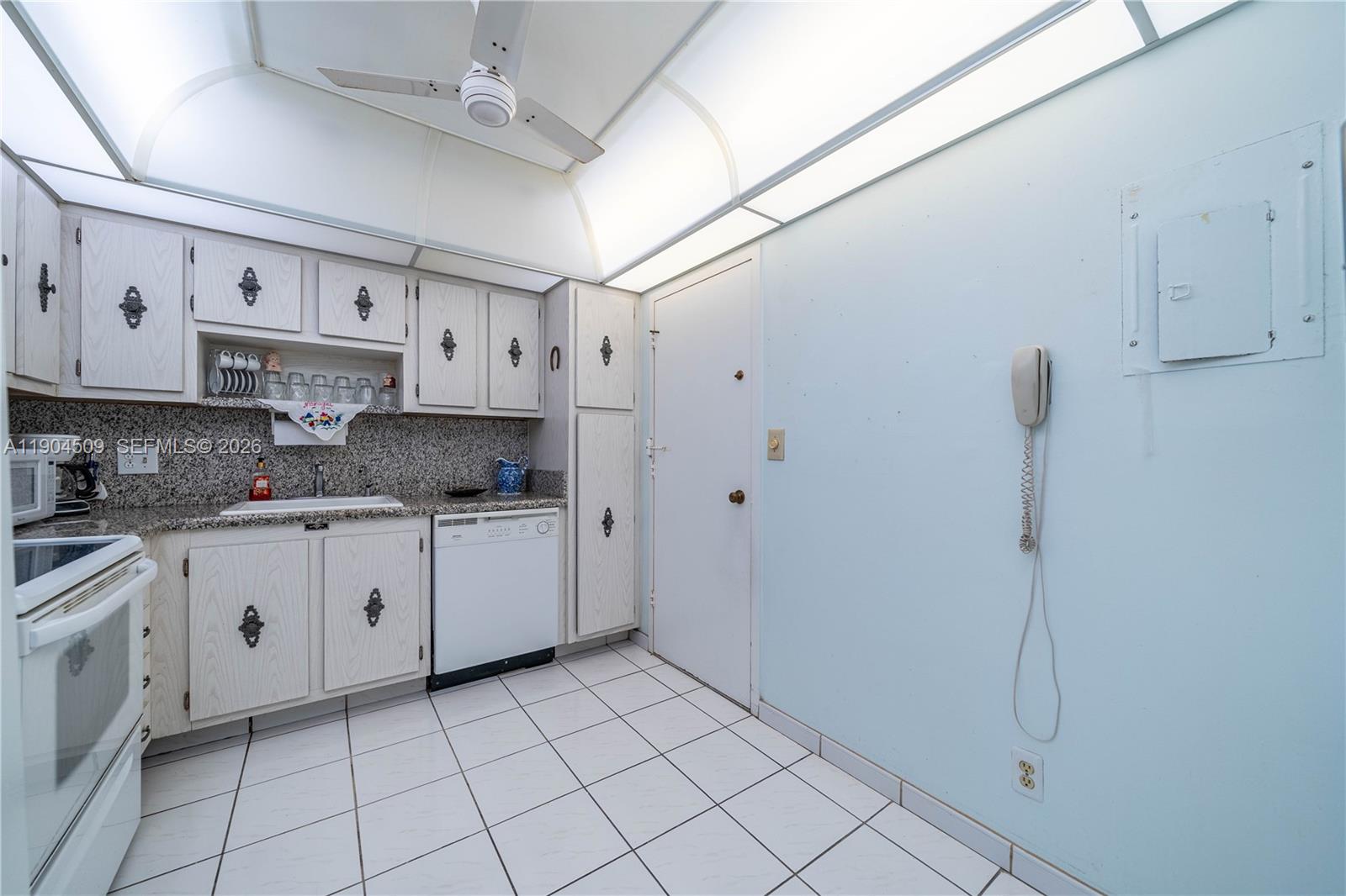 A kitchen features white cabinets, granite countertops, a tiled floor, and a ceiling fan — 3800 S Ocean Dr, Hollywood FL 33019, HOLLYWOOD, FL
