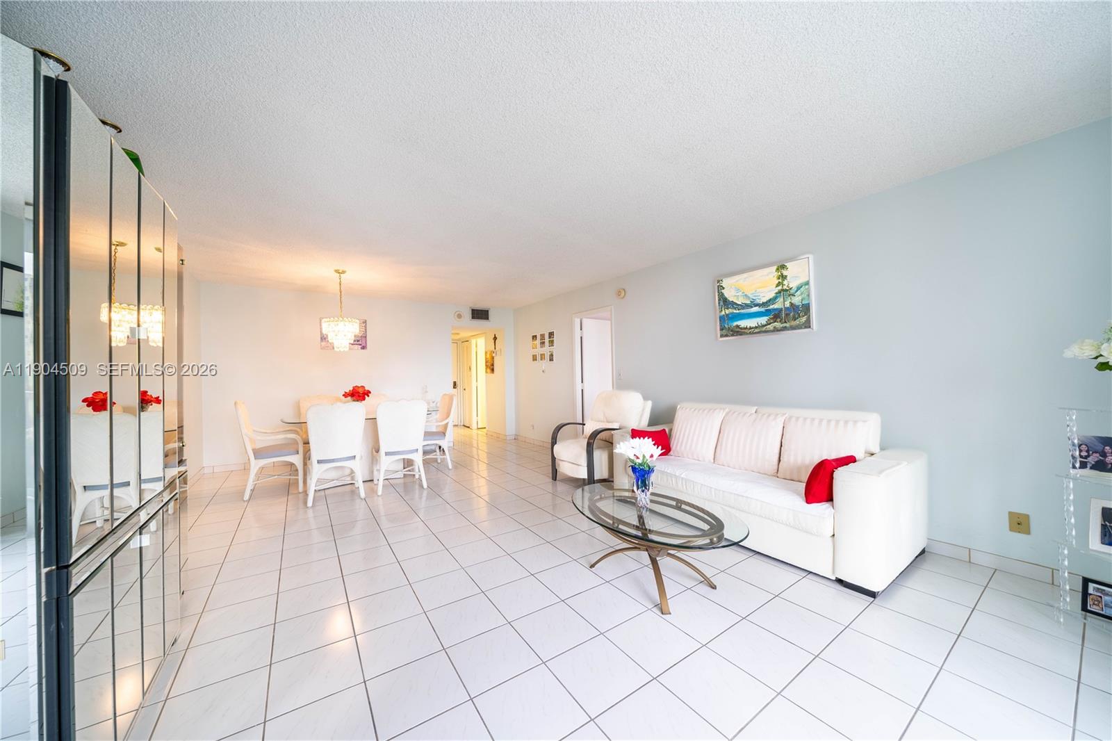 A living and dining area features white tile floors, a white sofa, and mirrored walls — 3800 S Ocean Dr, Hollywood FL 33019, HOLLYWOOD, FL