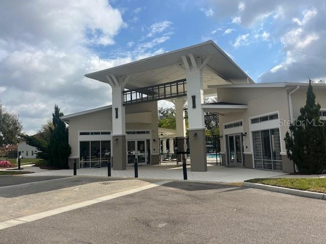 A modern community clubhouse entrance features a large covered breezeway and glass-paned doors — 2536 SHANTI DRIVE, KISSIMMEE, FL