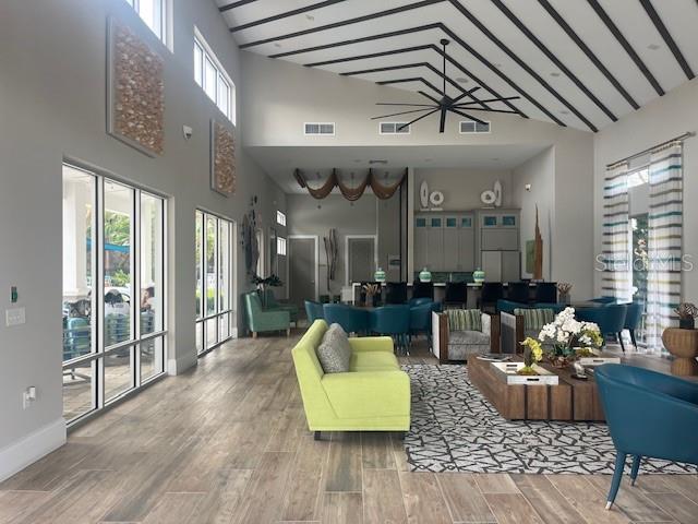 A spacious clubhouse lounge features vaulted ceilings with exposed beams, wood-look tile floors, and modern furniture — 2536 SHANTI DRIVE, KISSIMMEE, FL