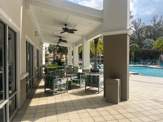 A covered outdoor patio features seating areas and ceiling fans overlooking a swimming pool — 2536 SHANTI DRIVE, KISSIMMEE, FL