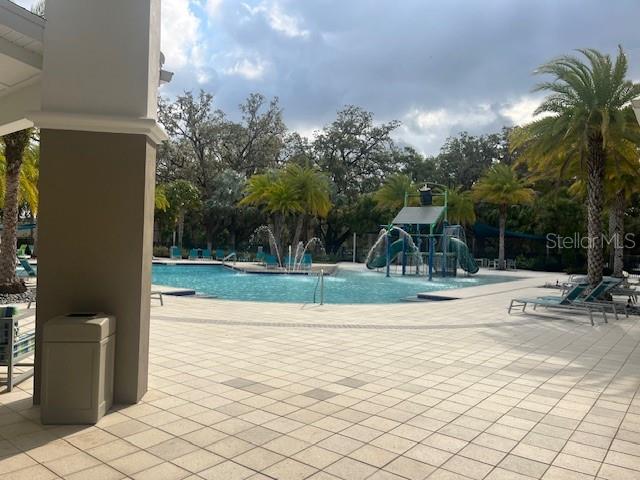 A swimming pool with a water play structure is surrounded by a paved patio area — 2536 SHANTI DRIVE, KISSIMMEE, FL