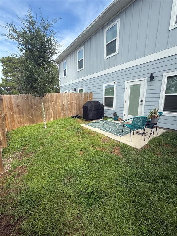 A small backyard features a concrete patio, a grill, two chairs, and a wooden fence — 105 PENTECOST WAY, FORT WALTON BEACH, FL