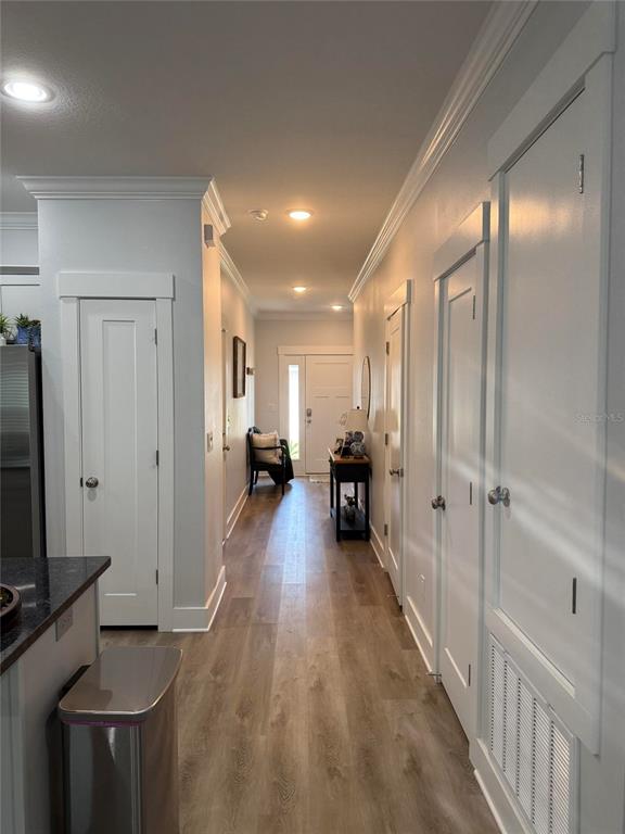 A hallway with light wood flooring, white doors, and recessed lighting leads to an entryway — 105 PENTECOST WAY, FORT WALTON BEACH, FL