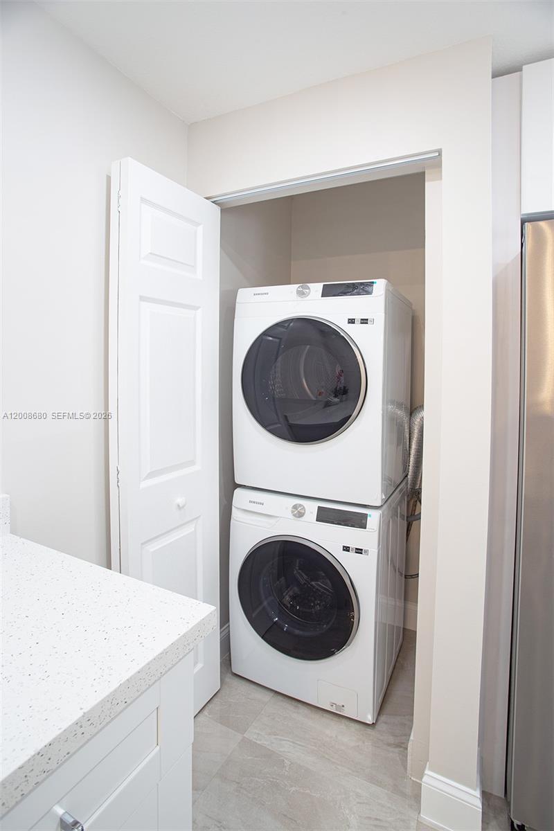 A stacked Samsung washer and dryer unit sits inside a closet next to a counter — 7527 S Oriole Blvd # 101, Delray Beach FL 33446, DELRAY BEACH, FL