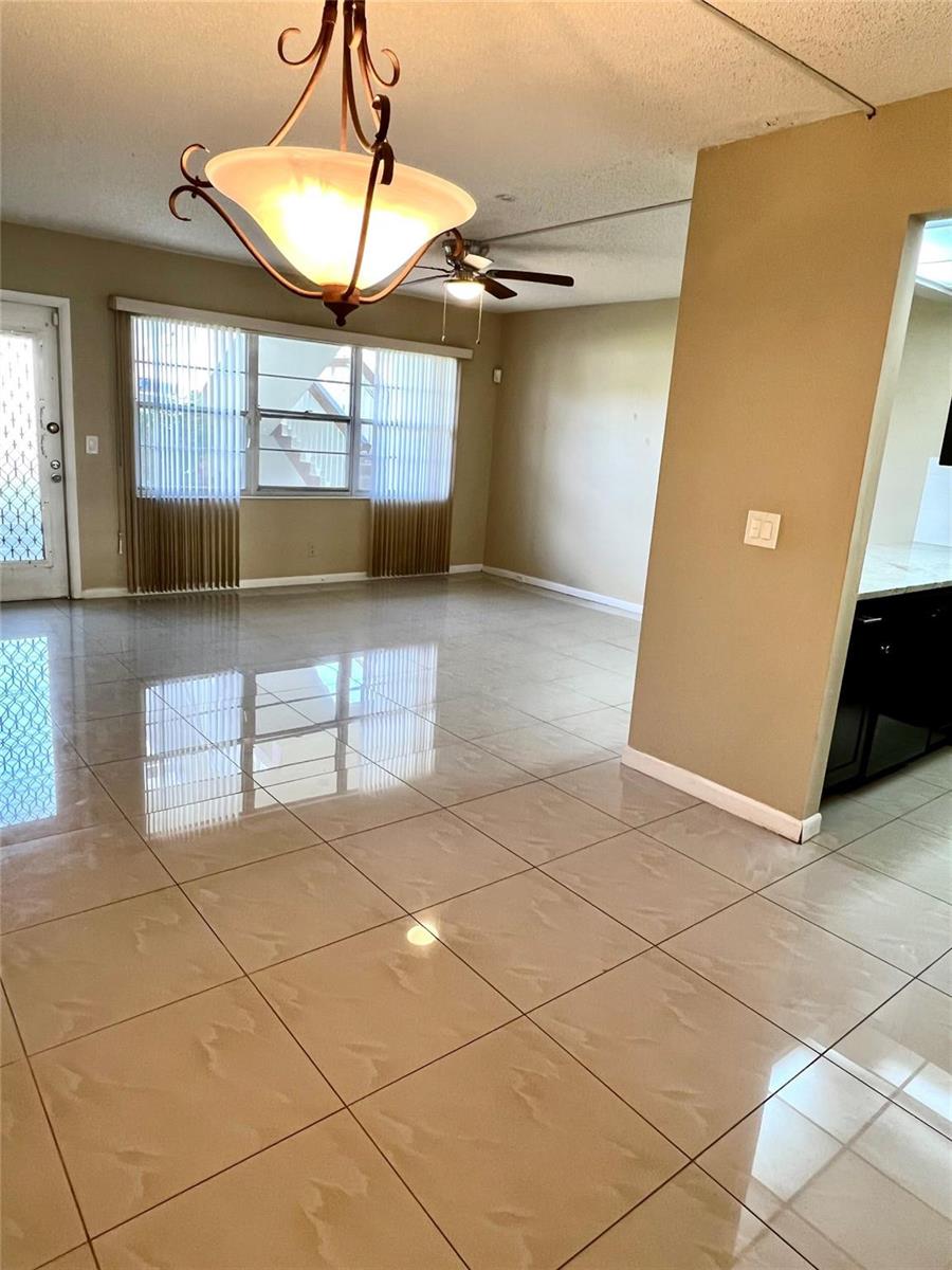 A living area features beige tile flooring, a chandelier, a ceiling fan, and vertical blinds — 517 Mansfield M # 517, Boca Raton FL 33434, BOCA RATON, FL