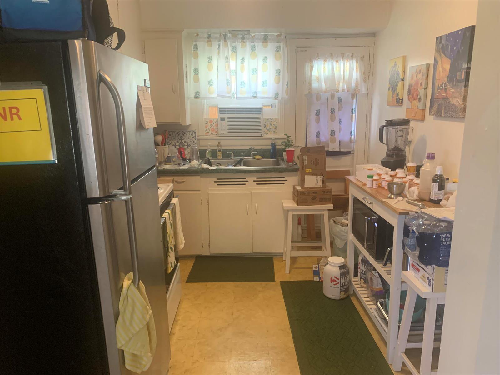 A small kitchen features white cabinets, stainless steel appliances, and a wooden kitchen island — 400 W Perry Street # d, Lantana FL 33462, LANTANA, FL