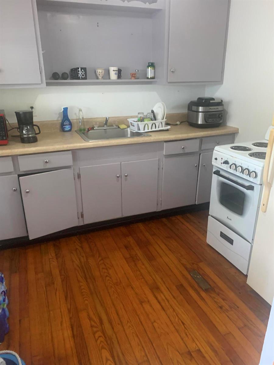 A kitchen features gray cabinets, a stainless steel sink, a white stove, and hardwood floors — 400 W Perry Street # d, Lantana FL 33462, LANTANA, FL