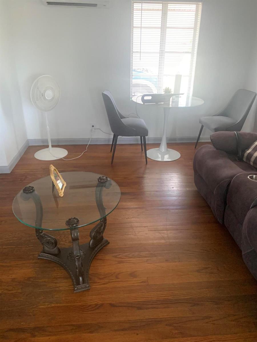 A living room features hardwood floors, a glass coffee table, a dining set, and a fan — 400 W Perry Street # d, Lantana FL 33462, LANTANA, FL