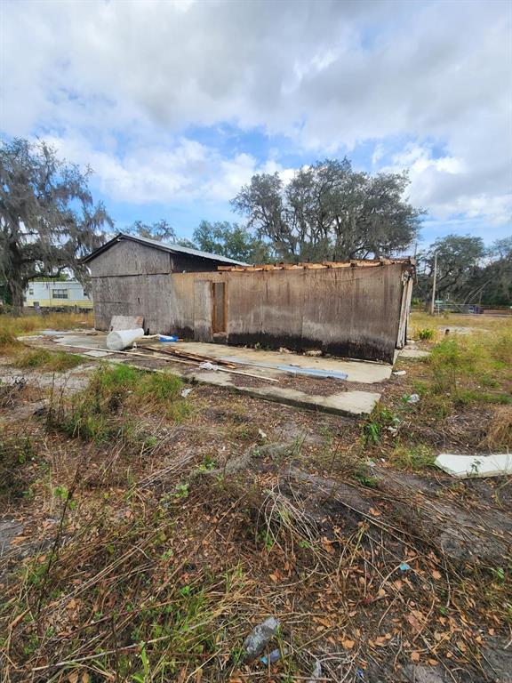 A dilapidated wooden structure stands on a concrete slab in an overgrown, grassy lot — 1409 WILKINSON DRIVE, PLANT CITY, FL