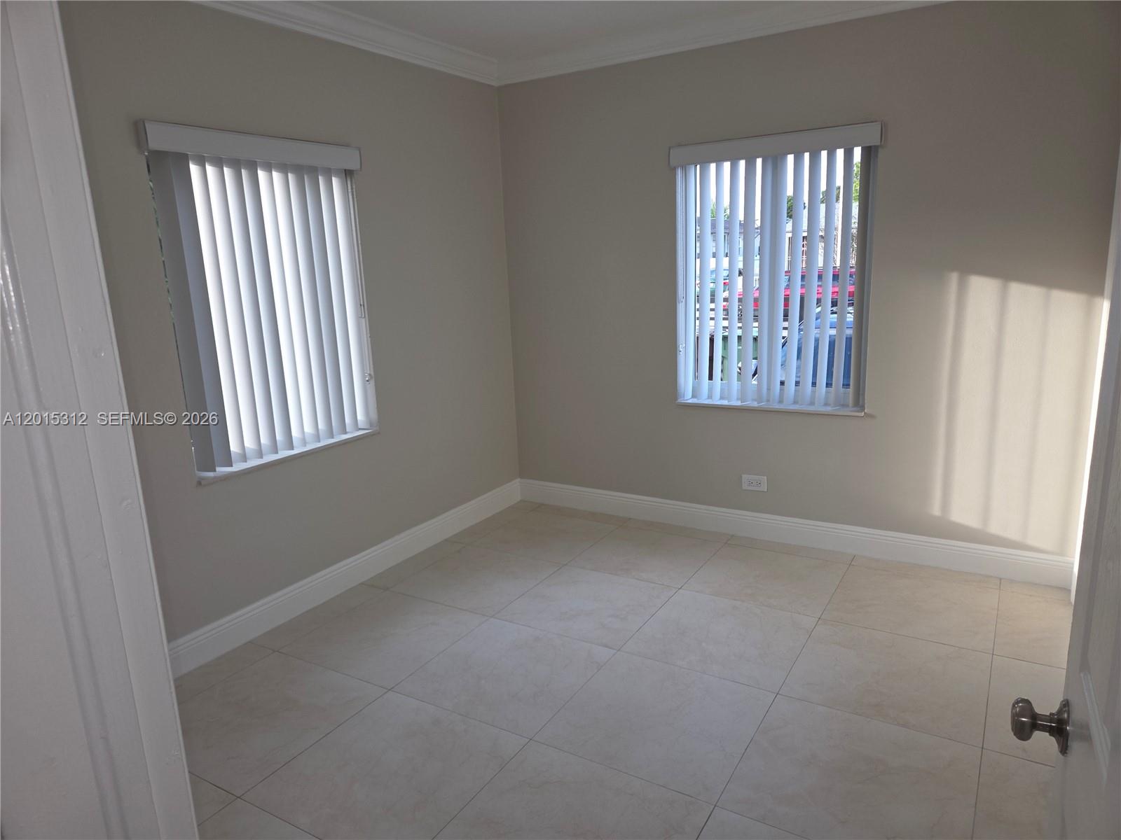 An empty room features beige walls, large floor tiles, and two windows with vertical blinds — 1680 E 5th Ave # 1690, Hialeah FL 33010, HIALEAH, FL