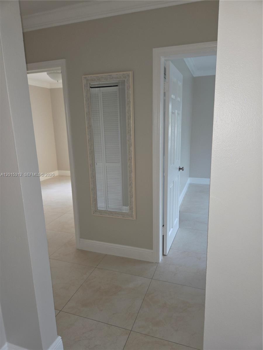 A hallway with light-colored tile flooring features a wall-mounted mirror between two open doorways — 1680 E 5th Ave # 1690, Hialeah FL 33010, HIALEAH, FL