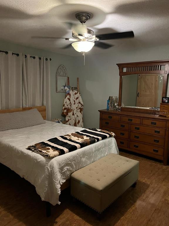 A bedroom features a wooden bed frame, a large dresser with a mirror, and a bench — 2700 SE 157TH LANE ROAD, SUMMERFIELD, FL