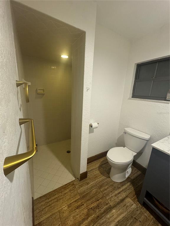 A bathroom features a walk-in shower, a white toilet, and wood-look tile flooring — 2700 SE 157TH LANE ROAD, SUMMERFIELD, FL
