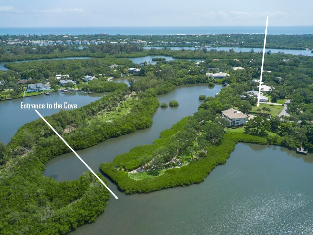An aerial view shows a coastal cove surrounded by dense vegetation and several residential homes — 2660 Riverview Court, Vero Beach FL 32963, VERO BEACH, FL