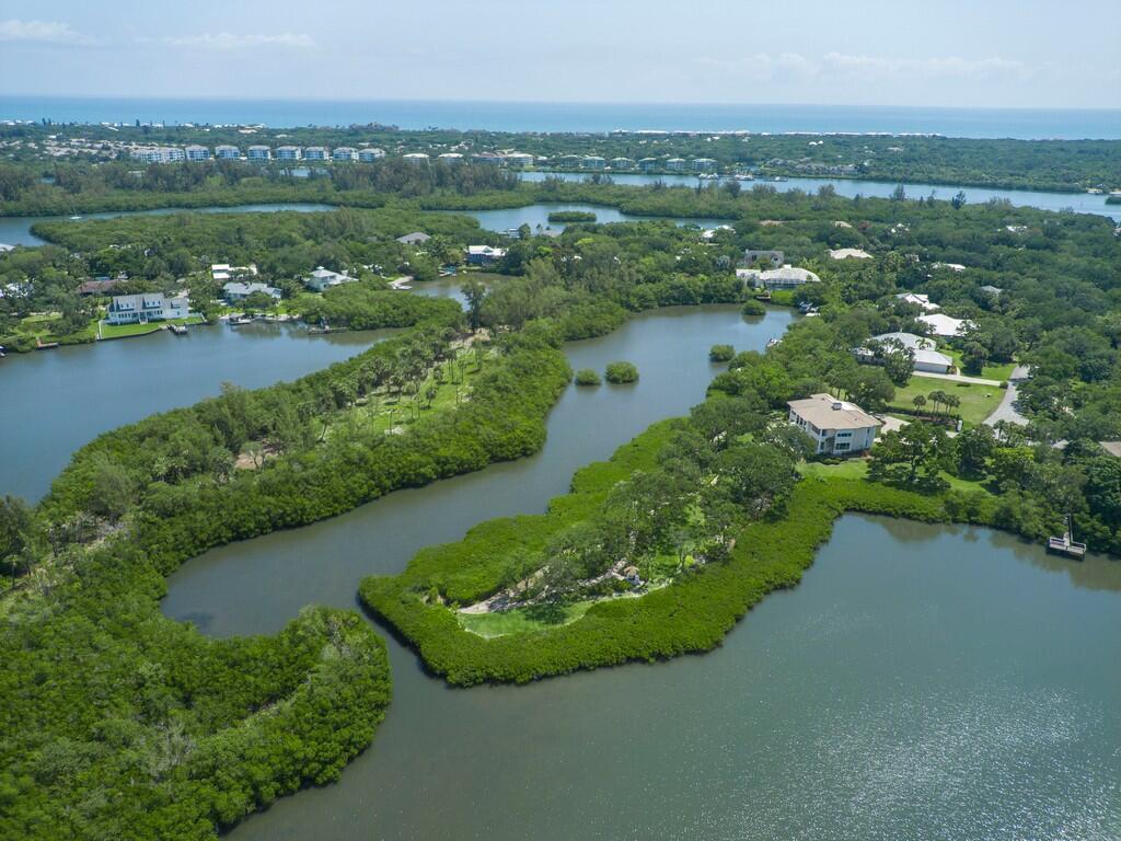 An aerial view shows houses nestled among dense mangroves and winding waterways near the ocean — 2660 Riverview Court, Vero Beach FL 32963, VERO BEACH, FL
