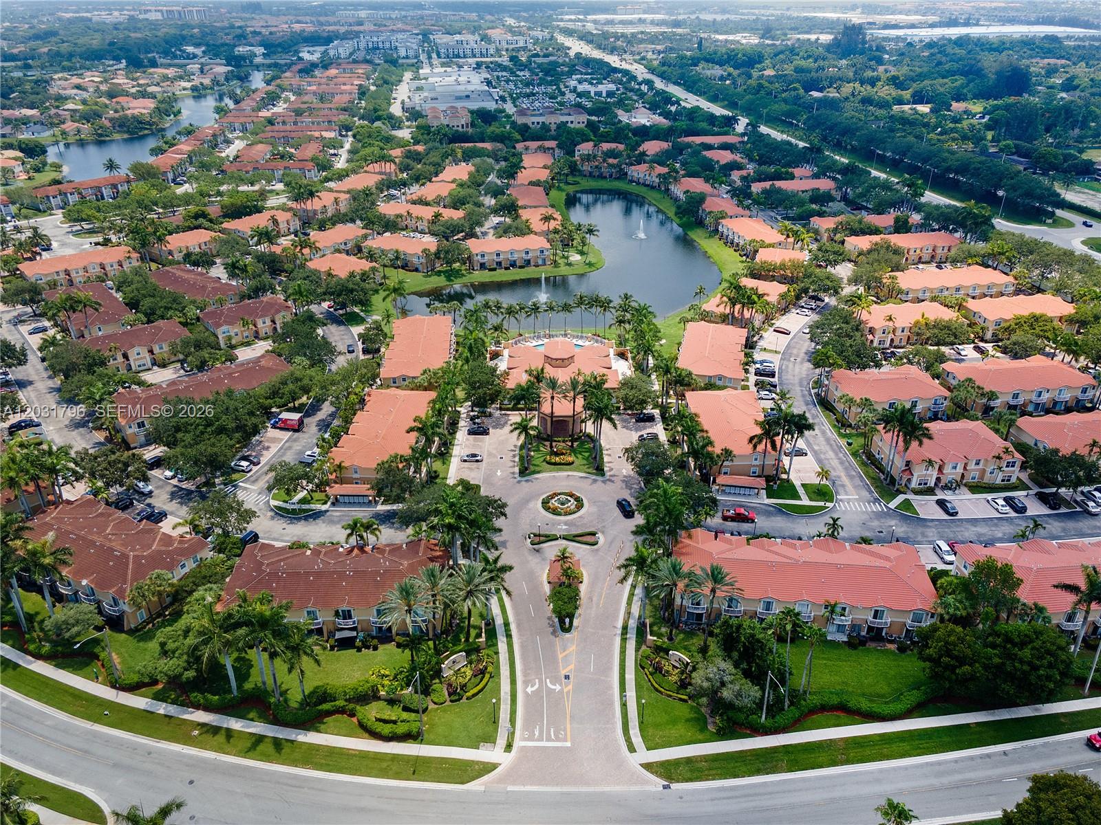 An aerial view of a residential complex featuring multi-story buildings, a central lake, and landscaping — 3073 SW 128th Ave # 109, Miramar FL 33027, MIRAMAR, FL
