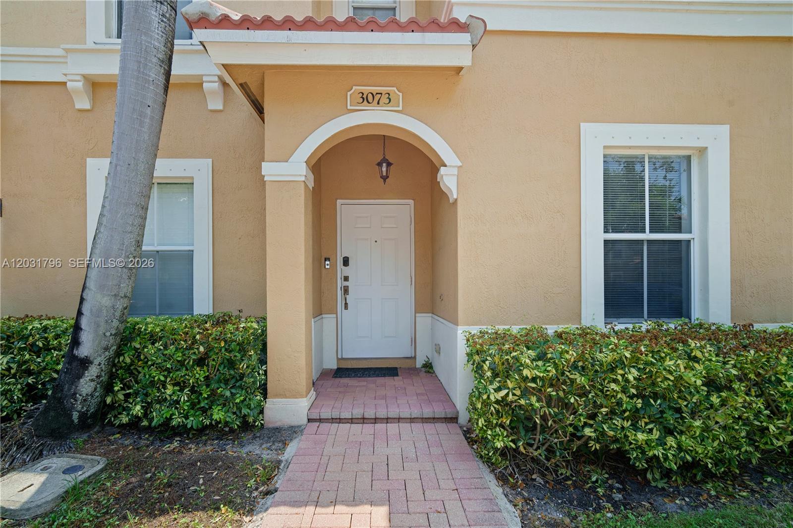 The exterior of a tan house features a white front door under a small archway — 3073 SW 128th Ave # 109, Miramar FL 33027, MIRAMAR, FL