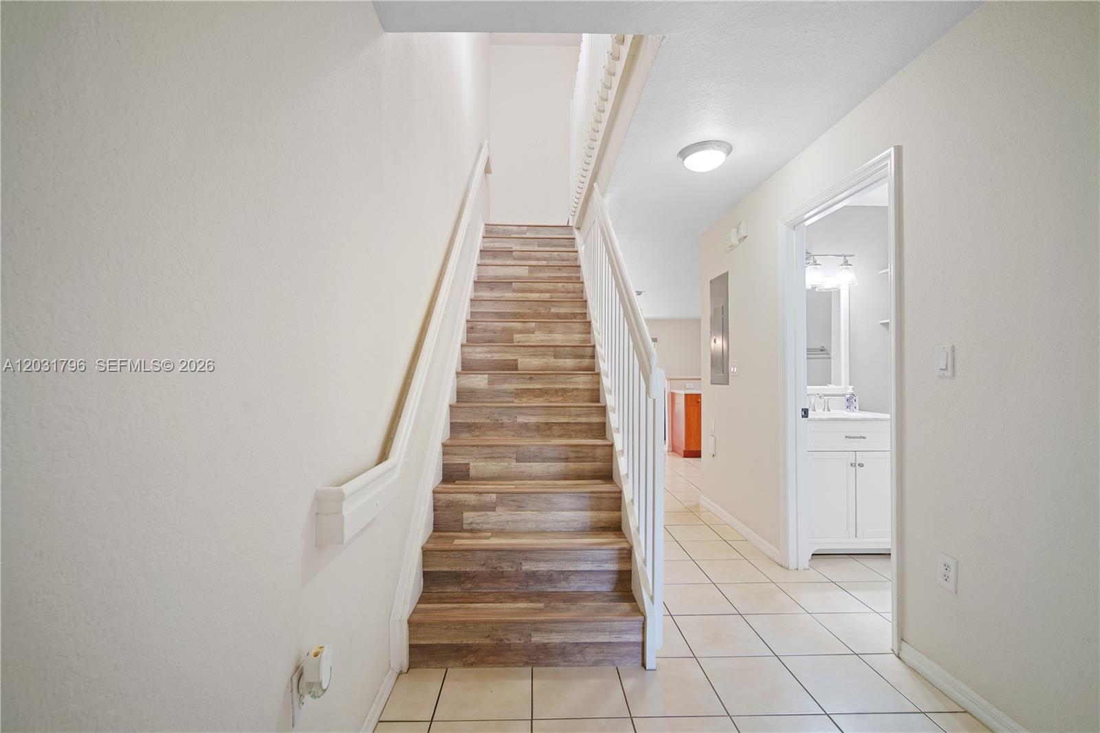 A staircase with wood-look treads leads upward next to a hallway with a bathroom — 3073 SW 128th Ave # 109, Miramar FL 33027, MIRAMAR, FL