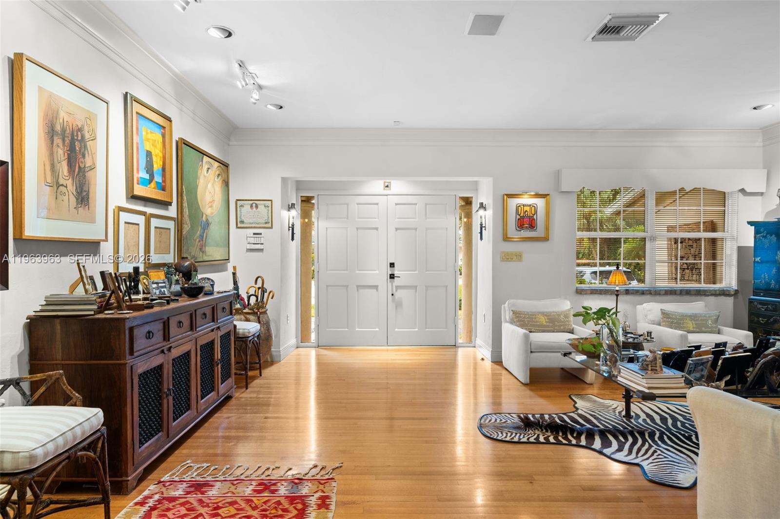 A bright entryway features hardwood floors, a wooden console table, and white double front doors — 1255 Algardi Ave, Coral Gables FL 33146, CORAL GABLES, FL