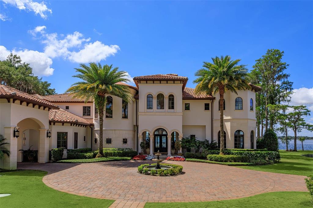 A large Mediterranean-style house with a circular brick driveway, a central fountain, and palm trees — 11900 LAKE BUTLER BOULEVARD, WINDERMERE, FL