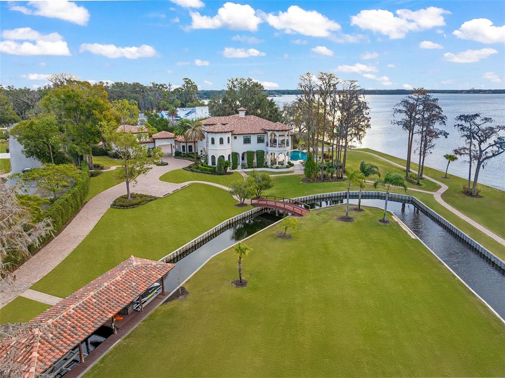 An aerial view of a waterfront estate featuring a large house, pool, and boat dock — 11900 LAKE BUTLER BOULEVARD, WINDERMERE, FL