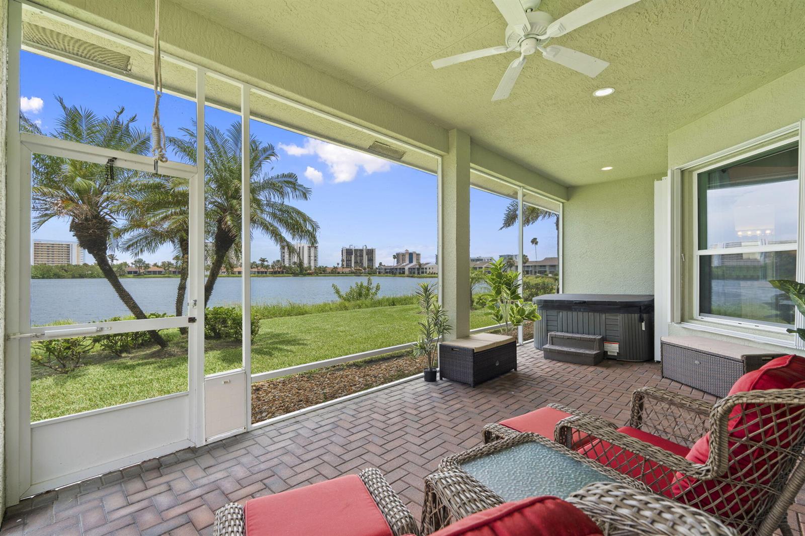 A screened-in patio with brick flooring, a hot tub, and a view of a lake — 3320 Caracal Drive, Fort Pierce FL 34949, FORT PIERCE, FL