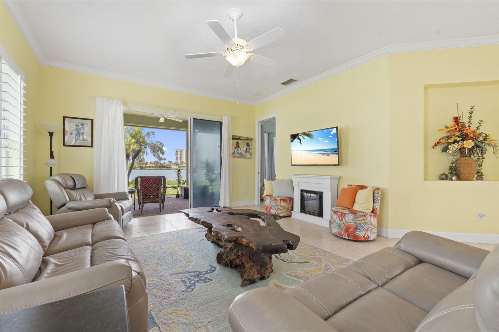 A living room with yellow walls, a live-edge wood coffee table, and a sliding glass door — 3320 Caracal Drive, Fort Pierce FL 34949, FORT PIERCE, FL