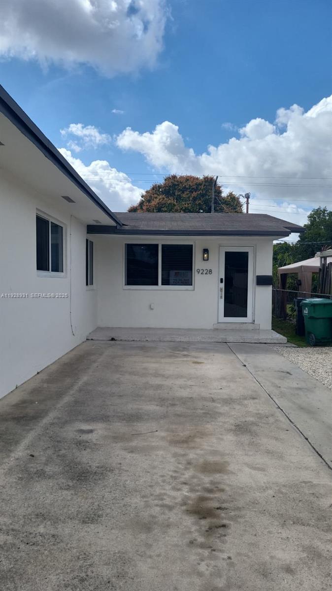 A white exterior house features a concrete driveway, a front door, and a window — 9228 SW 37th St # 9228, Miami FL 33165, MIAMI, FL