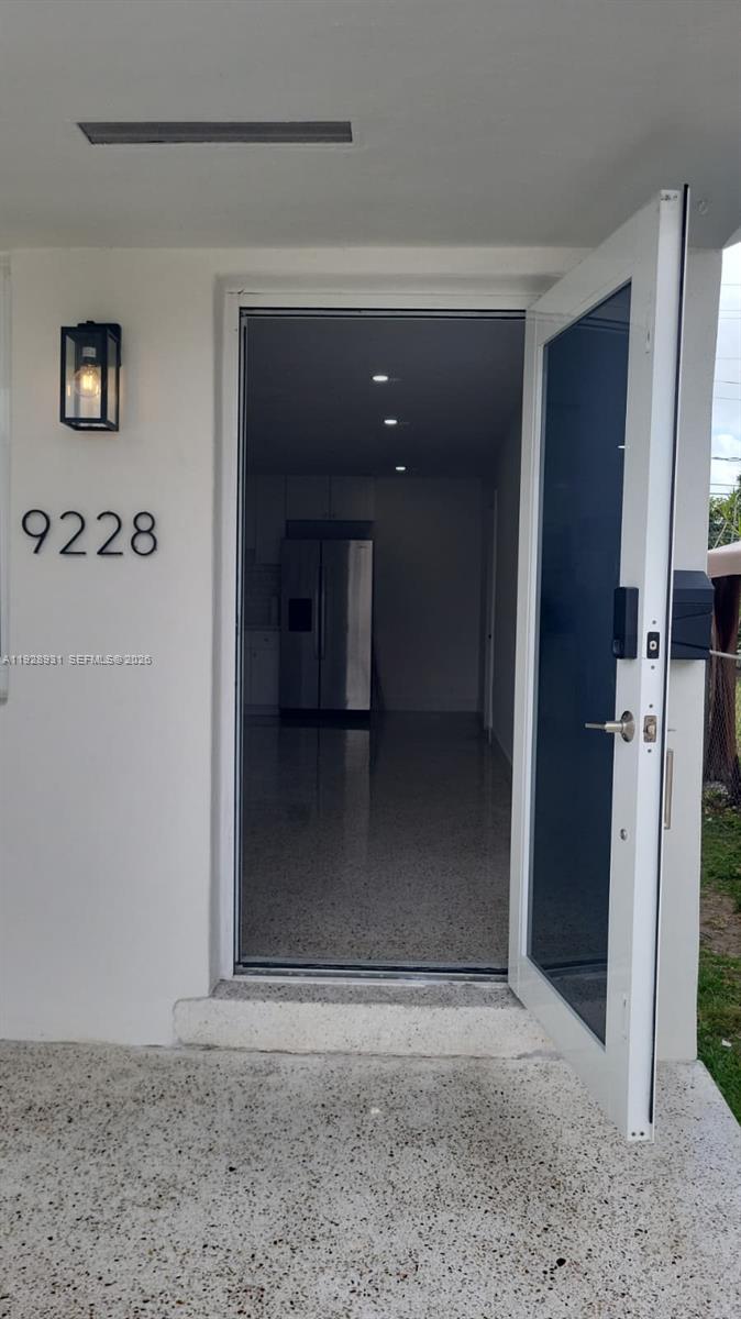 An open front door reveals a kitchen with stainless steel appliances and terrazzo flooring — 9228 SW 37th St # 9228, Miami FL 33165, MIAMI, FL