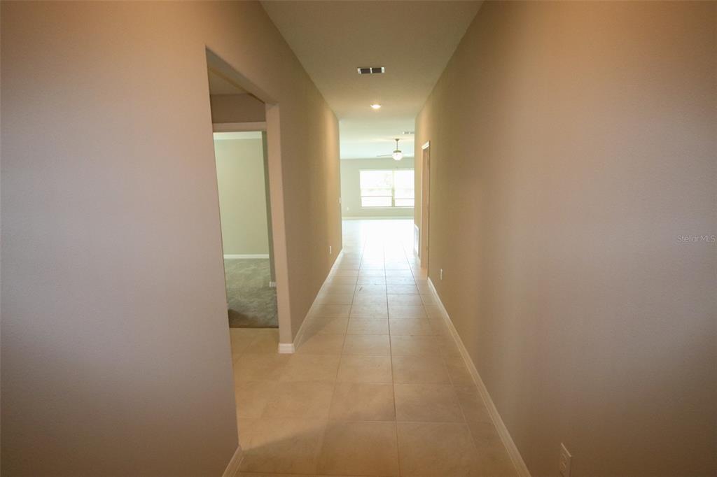 A tiled hallway leads from a doorway toward a bright, open living area — 10347 ALDER GREEN DRIVE, RIVERVIEW, FL