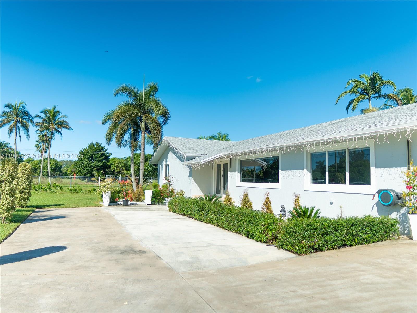 A single-story white house with a concrete driveway and palm trees under a blue sky — 19245 SW 188th St, Miami FL 33187, MIAMI, FL