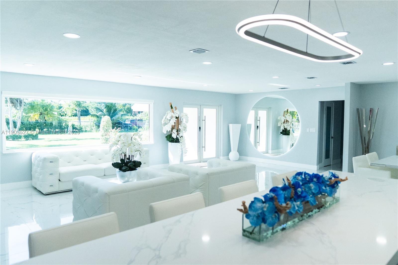 A bright, modern living and dining area features white tufted furniture and marble flooring — 19245 SW 188th St, Miami FL 33187, MIAMI, FL